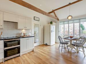 uma cozinha com armários brancos e uma mesa com cadeiras em 2 Bed in Bamburgh 90061 em Chatton