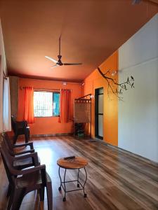 a living room with orange walls and a table and chairs at Sai Homestay in Malvan
