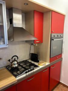 La cuisine est équipée de placards rouges et d'un four avec plaques de cuisson. dans l'établissement Centro storico Residenza di charme, à Rimini