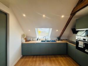 an attic kitchen with a sink and a window at Les Chênes en duplex in Ploemeur