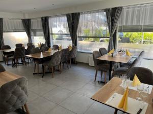 a restaurant with wooden tables and chairs and windows at Hotel Restaurant du Moulin in Fleurier