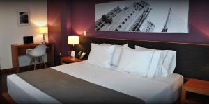 Habitación de hotel con cama con almohadas blancas en Hotel y Tú Expo en Guadalajara