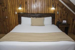 a bedroom with a large white bed with wooden walls at Hotel El Tirol in Alto del Roble