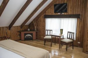 Hotel El Tirol في Alto del Roble: غرفة نوم بسرير وطاولة وتلفزيون