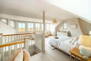 1 dormitorio blanco con 1 cama y escalera en White Horses by Big Skies Cottages, en Blakeney