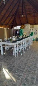 una mesa larga con mesas blancas y sillas blancas en BelaBela Guesthouse, en Bela-Bela