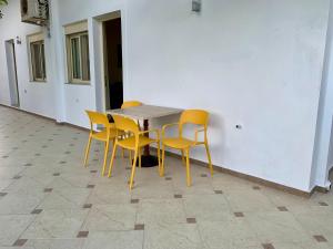 a table with yellow chairs sitting next to a wall at Duka Apts in Sarandë