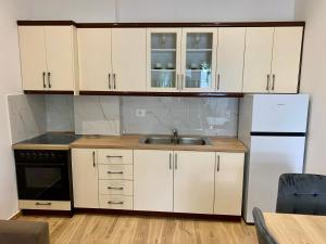 a kitchen with white cabinets and a sink and a refrigerator at Duka Apts in Sarandë