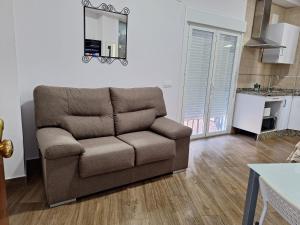 un sofá marrón en una sala de estar con cocina en TourismCasa, en Dos Hermanas