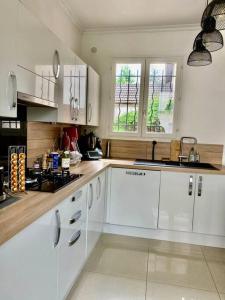 a white kitchen with white cabinets and windows at Superbe Maison à Saint-Ouen in Saint-Ouen