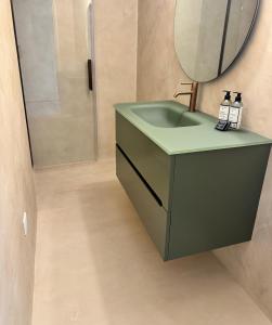 een badkamer met een groene wastafel en een spiegel bij Hotel Résidence San Roccu in Saint-Florent