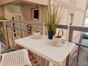 - deux tasses de café sur une table blanche sur un balcon dans l'établissement Studio apartman na plaži, à Rafailovici