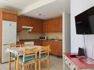 a kitchen with wooden cabinets and a table with chairs at Casa Vega in El Cotillo