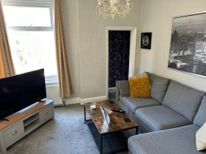 een woonkamer met een bank en een flatscreen-tv bij 1 bedroom spacious apartment in Lytham St Annes