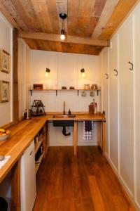 a kitchen with white cabinets and a wooden floor at Self contained romantic Farmstay in Waipara wine country with bath and fire in Waipara