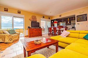a living room with a yellow couch and a table at Amazing Mediterranean view Villa Oliva Zaboric in Zaboric