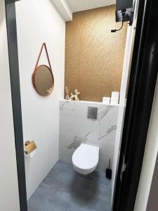 uma casa de banho com um WC branco e um espelho. em Nieuw! The West Wing Bloemendaal em Bloemendaal
