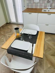 einem Küchentisch mit zwei weißen Stühlen und einem Tisch mit Tellern und Gläsern in der Unterkunft civico 250 in Pescara
