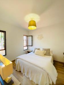 a white bedroom with a white bed and a yellow light at Bungalow Paraiso in Callao Salvaje