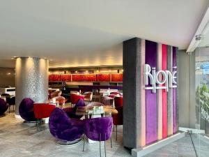 a restaurant with purple chairs and tables in a lobby at Rioné Hotel Boutique in Cuenca