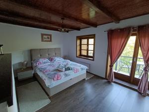 a bedroom with a bed and a large window at Kuća za odmor Djedov šešir in Oriovčić