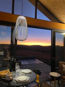 a dining table with a view of the sunset at Soular Lodge e Fazenda in São Francisco de Paula