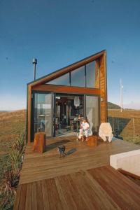 Soular Lodge e Fazenda في ساو فرانسيسكو دي باولا: منزل على شرفة يجلس عليها شخص على كرسي