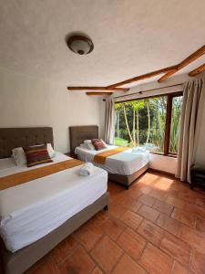 sypialnia z 2 łóżkami i dużym oknem w obiekcie ApartaHotel La Leyenda w mieście Villa de Leyva