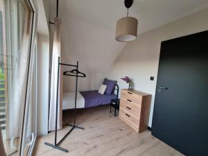 a bedroom with a bed and a dresser and a door at Pole Lawendowe Sielsko - domek na polu in Pawłów