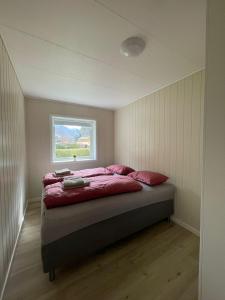a bedroom with a bed with pink sheets and a window at Fint hus i Flåm in Aurland