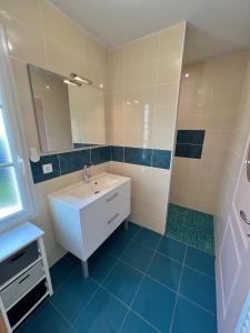 een badkamer met een witte wastafel en een spiegel bij La Maison du Bonheur in Rochefort