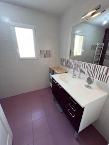 een badkamer met een wastafel en een spiegel bij La Maison du Bonheur in Rochefort