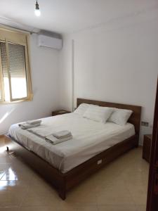 a bedroom with a large bed with white sheets and a window at Lungomare Apartament Sea View in Vlorë