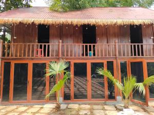 Ce chalet en bois dispose d'une terrasse avec des palmiers. dans l'établissement Homestay Long Cốc thanh biên, 