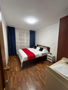 1 dormitorio con 1 cama con manta roja y blanca en Апартаменты в центре города, en Aktobe