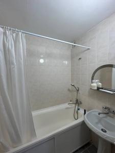 a bathroom with a shower curtain and a sink at Апартаменты в центре города in Aktobe