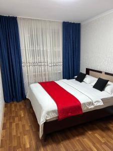 1 dormitorio con 1 cama grande con manta roja en Апартаменты в центре города en Aktobé