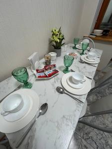 a table with glasses and plates and spoons on it at Апартаменты в центре города in Aktobe