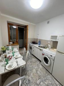 a kitchen with a table and chairs and a sink and a washing machine at Апартаменты в центре города in Aktobe