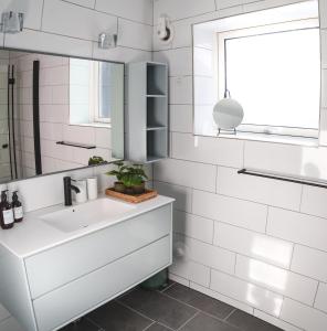 a white bathroom with a sink and a mirror at The Black House Tuapannguit 48 in Nuuk