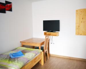 a room with a bed and a desk with a television at Tourist Farm Pri Požarju in Knežak
