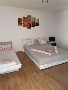 a white bedroom with two beds and a tv at Apartman Amela in Mostar