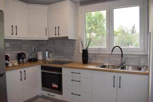 a kitchen with white cabinets and a sink and a window at The Valley House in Kanakádes