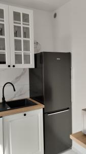 a kitchen with a black refrigerator and white cabinets at Apartament ZDRÓJ in Jastrzębie Zdrój
