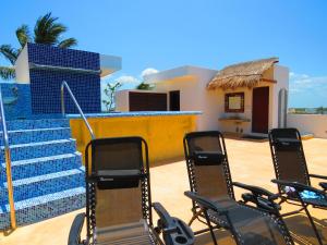 a group of chairs sitting on a patio with a house at Hotel Villas Ponto Holbox in Holbox Island
