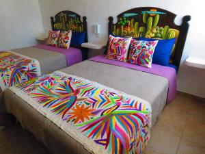 a room with two beds with colorful blankets and pillows at Villas ponto in Holbox Island