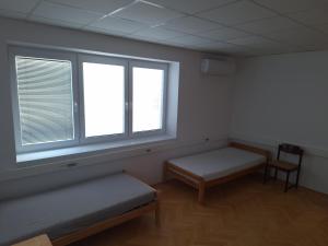 a room with two beds and a window and a chair at Apartmán Stummerova in Topoľčany