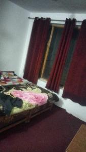 a bedroom with a bed and a window with red curtains at OYO Holidayinn in Kargil