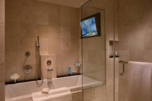 a bathroom with a tub and a shower with a tv at Millennium Knickerbocker Chicago in Chicago