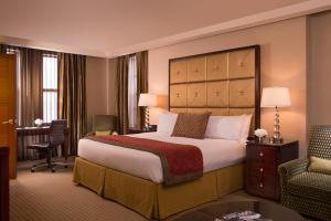a hotel room with a large bed and a desk at Millennium Knickerbocker Chicago in Chicago